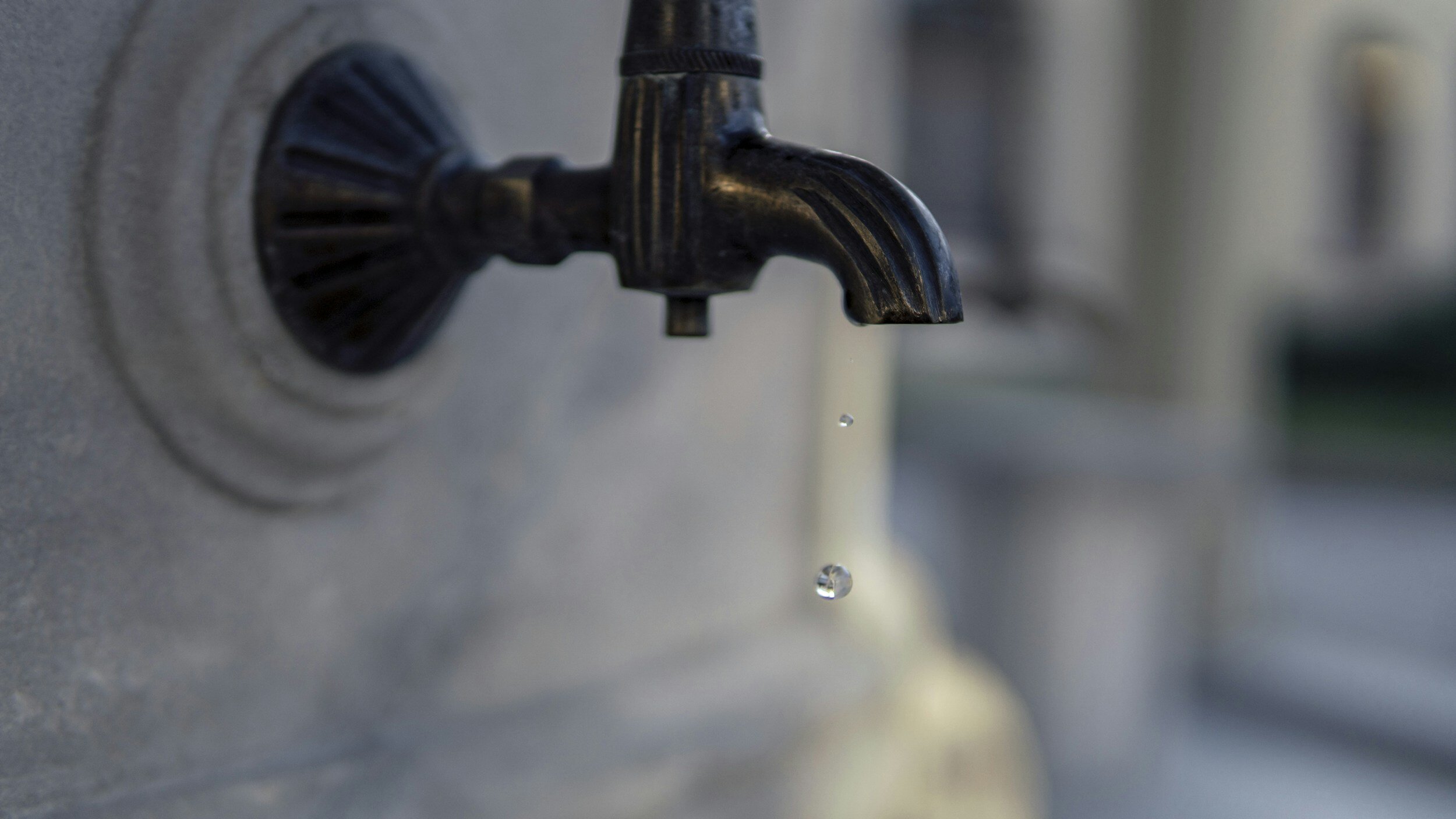 A water tap with a single droplet of water falling